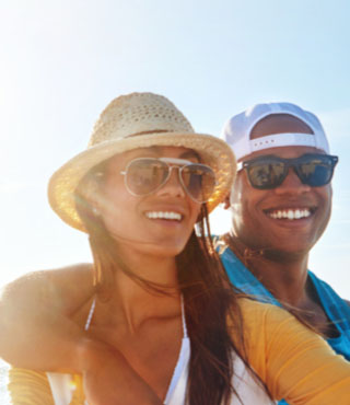 Couple taking a selfie on a beach trip, which they can protect with travel insurance.
