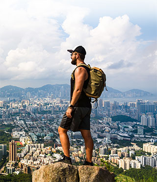 Backpacker on mountain overlooking city