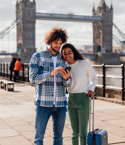 Couple in the U.K. smiling and looking at a travel app.