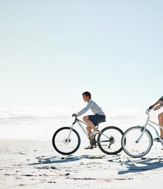 family riding bikes on beach