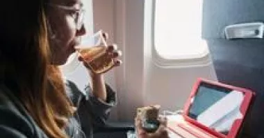 Person eating and drinking in plane seat