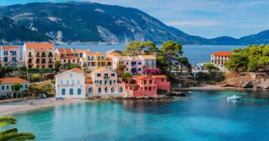 Read our Europe travel guide before traveling to see this view of Assos village in Greece with colorful houses and a lagoon.