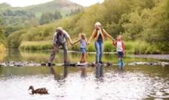 Grandparents and two children crossing a river