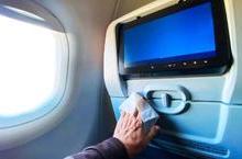 Hand wiping down airplane seatback tray