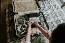 Person packing suitcase on bed