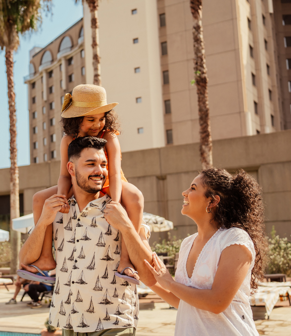 Couple with young daughter walking by hotel pool after looking for the best travel deals