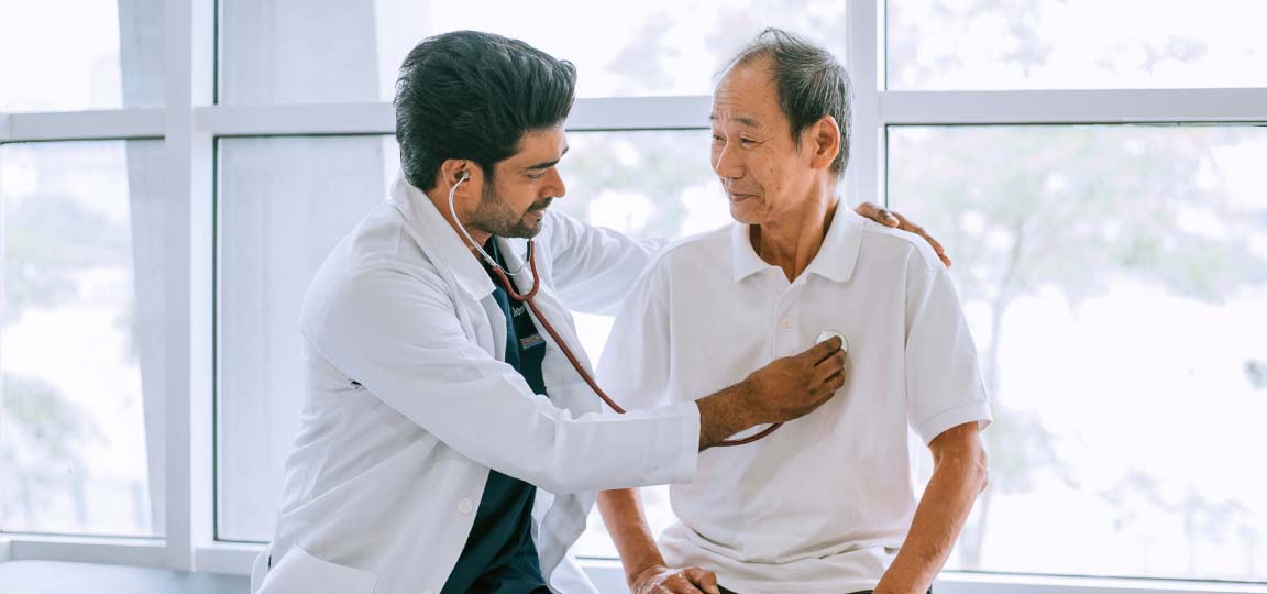 patient seeing a doctor on vacation having his heart checked with a stethoscope