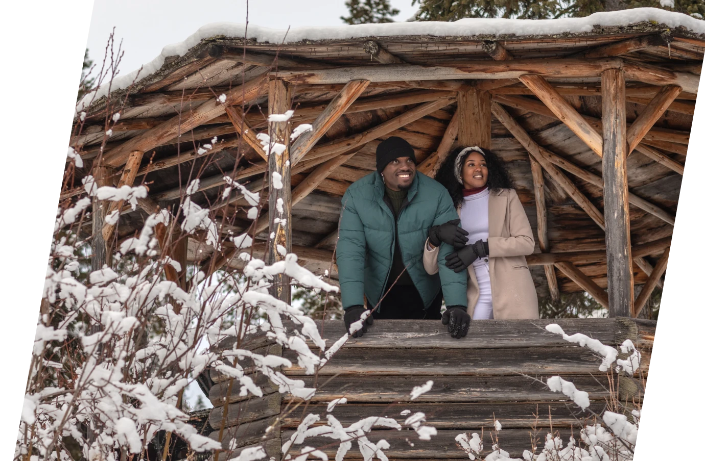 Couple with travel insurance for their all-inclusive trip under a gazebo looking at the snowy forest view