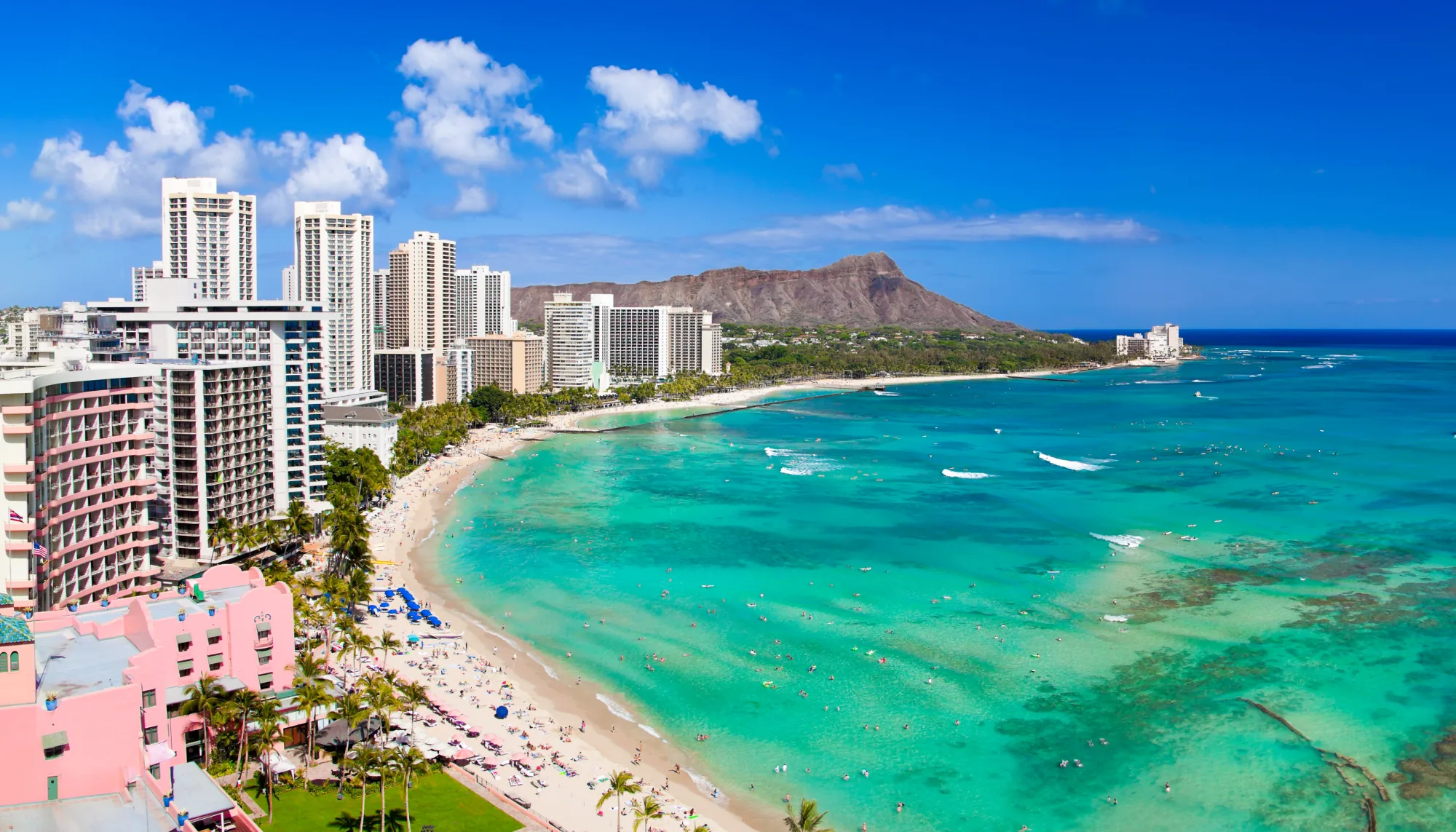 Aerial view of the beach, hotels, and mountains in Waikiki, prompting the question: "Are all-inclusive resorts worth it?"