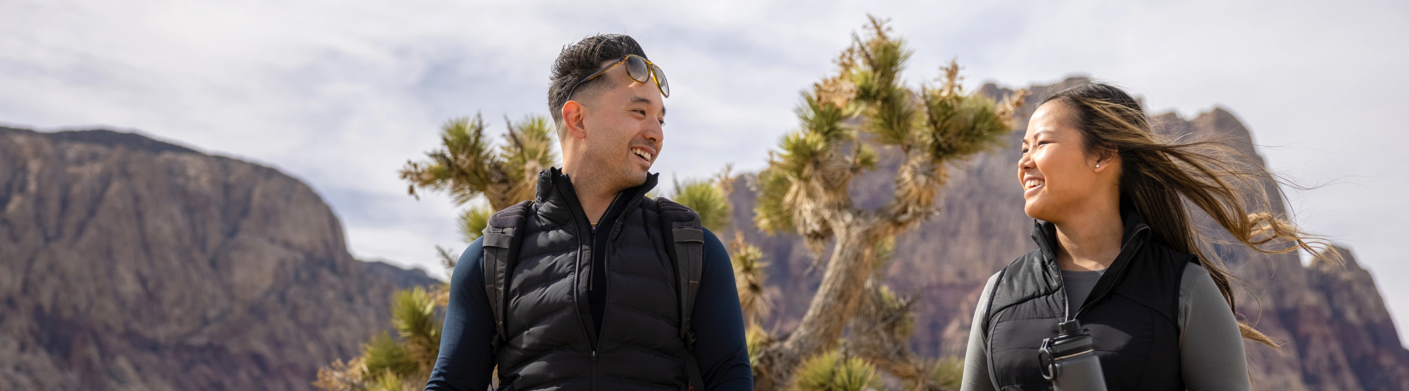 Couple, with travel insurance for Nevada, hiking in the desert and smiling at each other