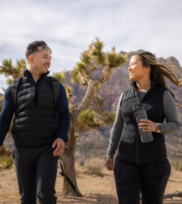 Couple, with travel insurance for Nevada, hiking in the desert and smiling at each other