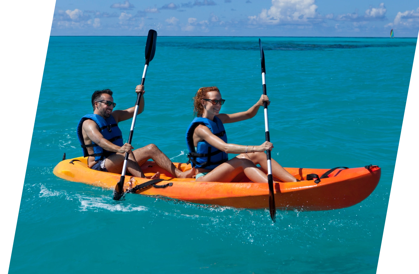 Couple with travel insurance for the Bahamas kayaking in the ocean with life jackets on