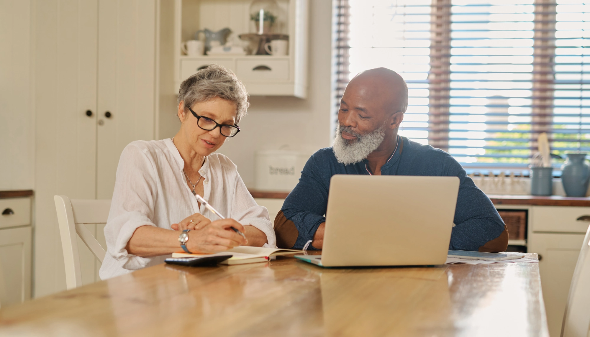 a couple in front of a laptop with a notebook, writing down our travel insurance claim tips 