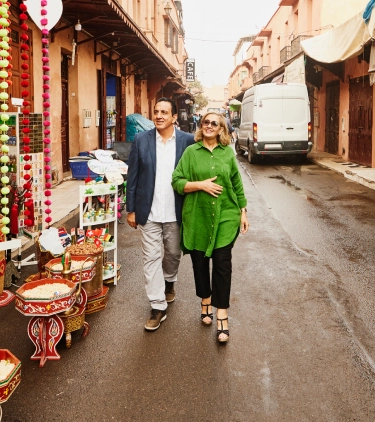 Middle-aged couple with flight insurance walking past spices in a market in Marrakech