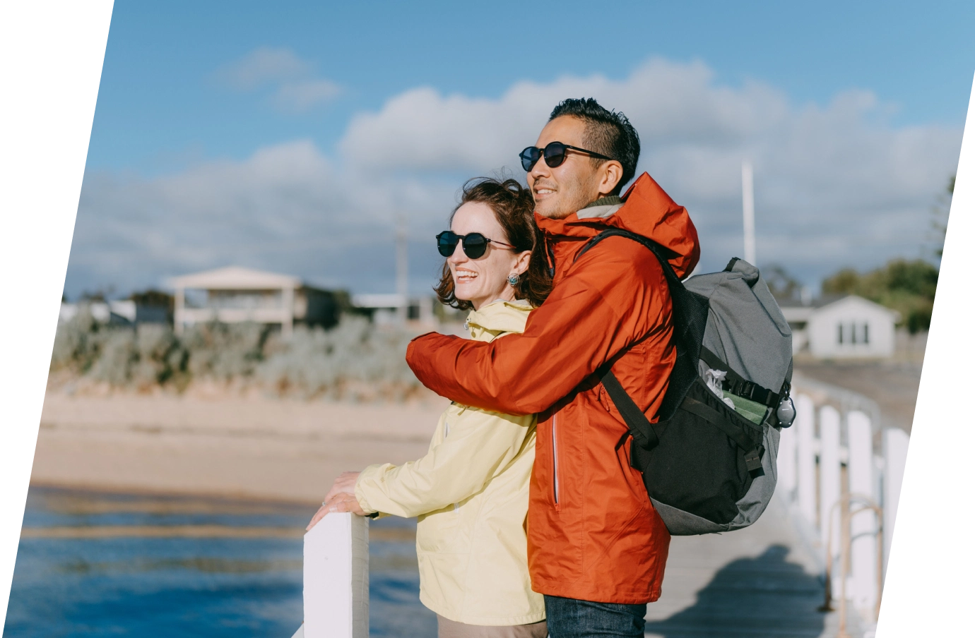 a couple with travel insurance for Australia, embracing and enjoying ocean views on a boardwalk 