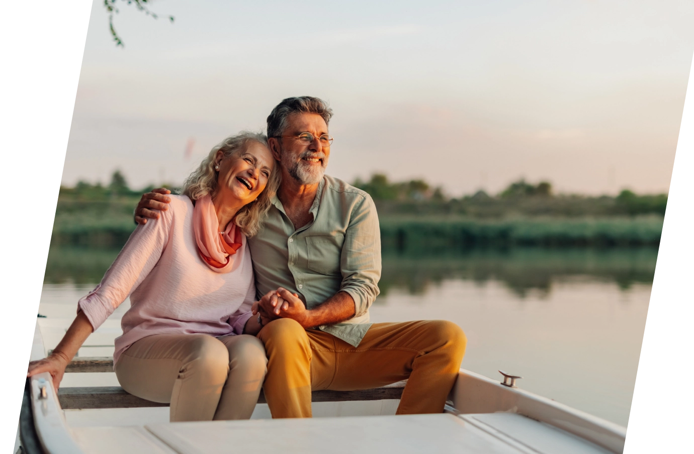 older couple with inexpensive travel insurance embracing on a boat in the lake at sunset