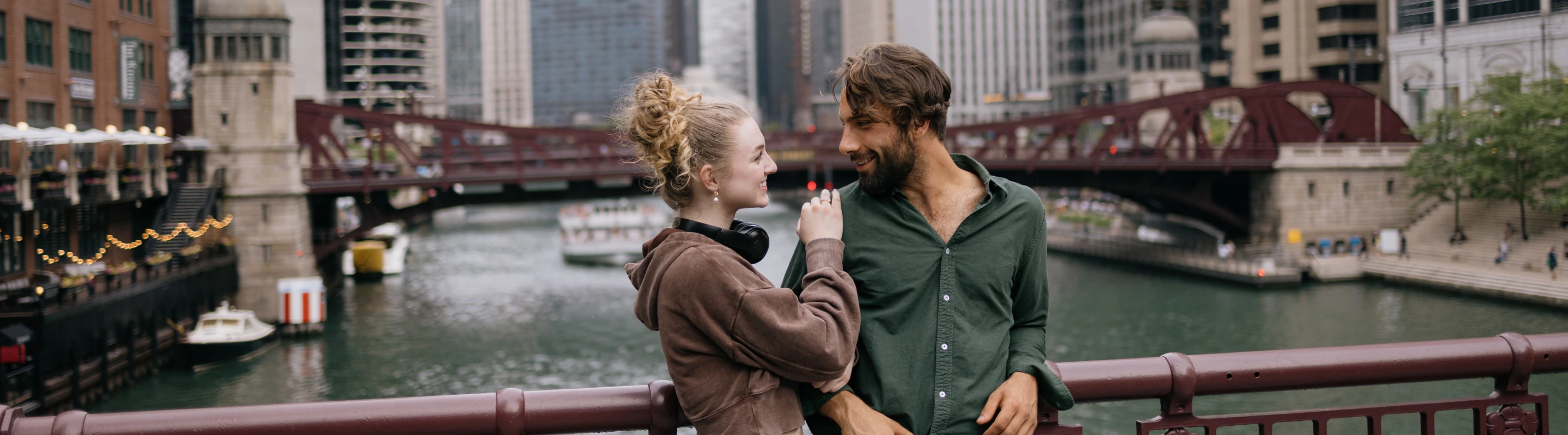 a couple shows affection on a red steel truss bridge in downtown Chicago, insured with travel insurance for Illinois 
