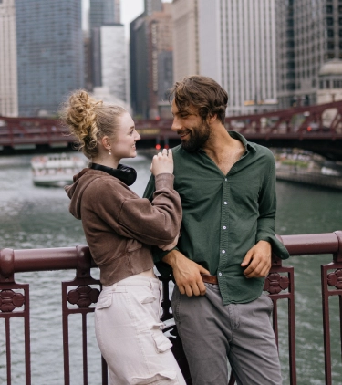 a couple shows affection on a red steel truss bridge in downtown Chicago, insured with travel insurance for Illinois 