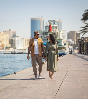 a middle eastern couple with travel insurance for the UAE enjoy a walk along Dubai Marina's waterfront