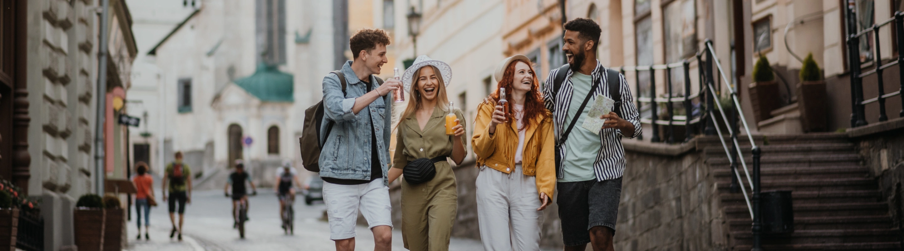 two couples with travel insurance for Europe, laughing and enjoying drinks in an alleyway in Europe