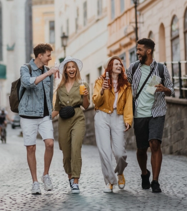 two couples with travel insurance for Europe, laughing and enjoying drinks in an alleyway in Europe