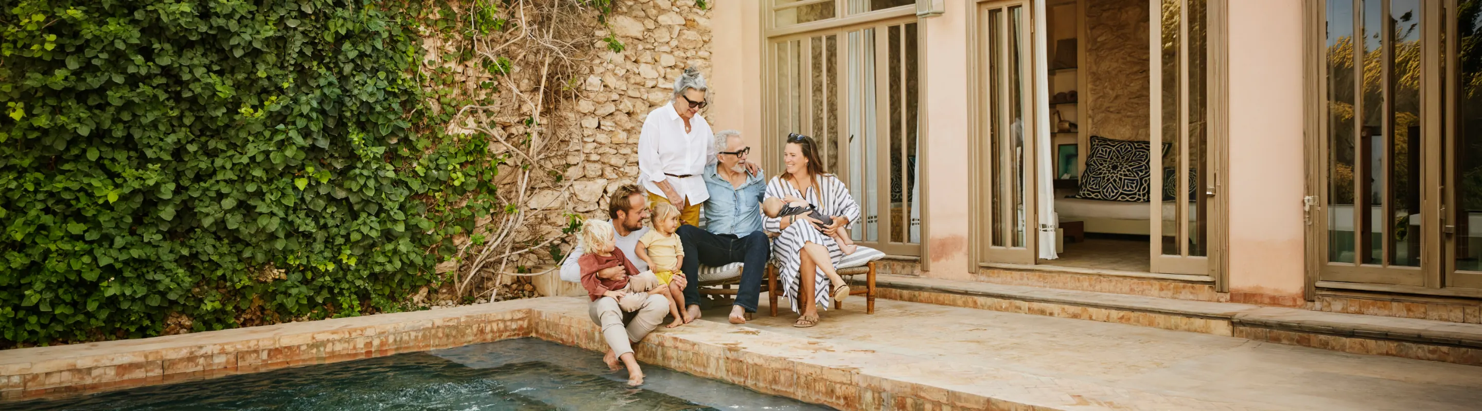 Multigenerational family sitting by the pool and talking about travel insurance for Africa