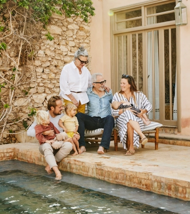 Multigenerational family sitting by the pool and talking about travel insurance for Africa