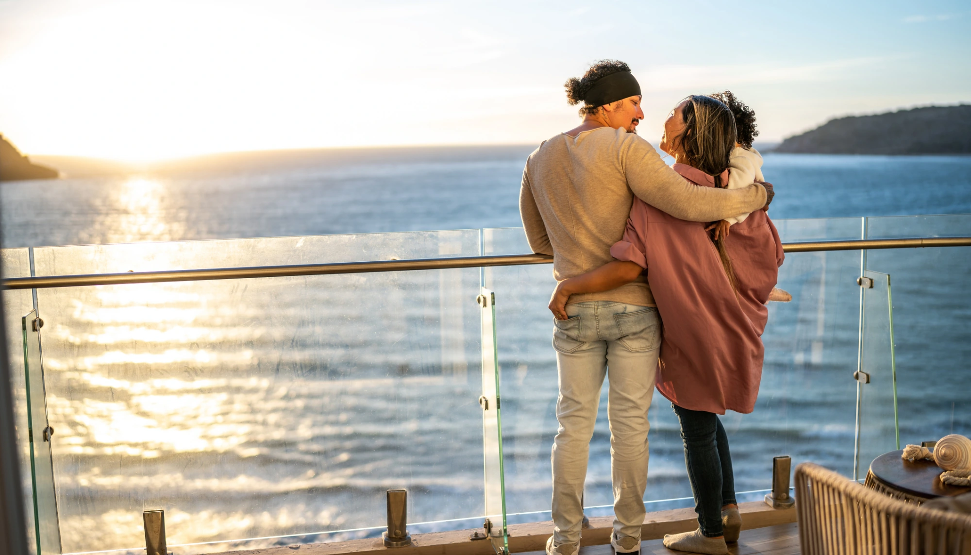 Parents and young child embracing on a cruise ship overlooking the ocean after reading a cruise safety guide