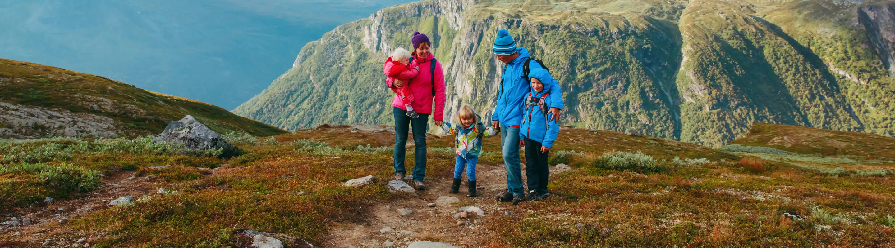 Parents with travel insurance for Europe hiking with their three children in the mountains in Norway