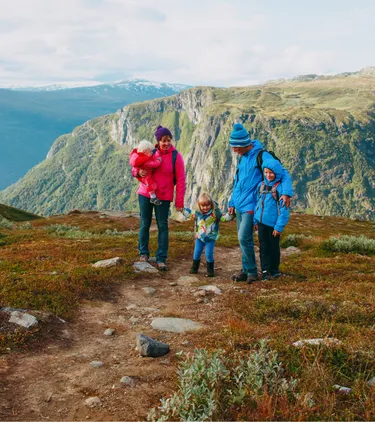 Parents with travel insurance for Europe hiking with their three children in the mountains in Norway