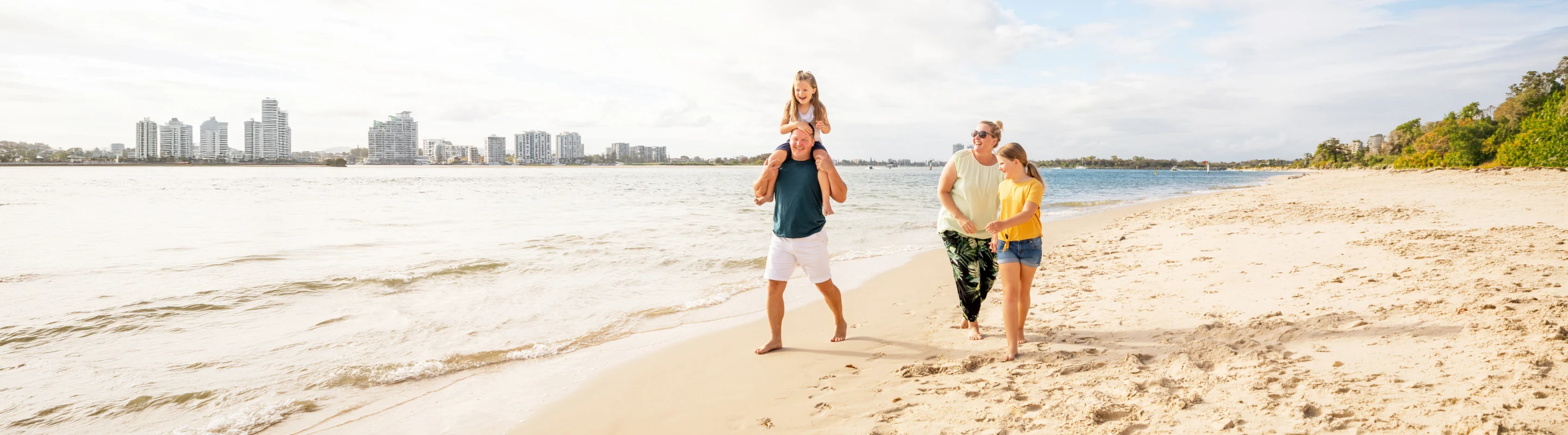 a family of four with travel insurance for Australia, enjoying a walk by the ocean together