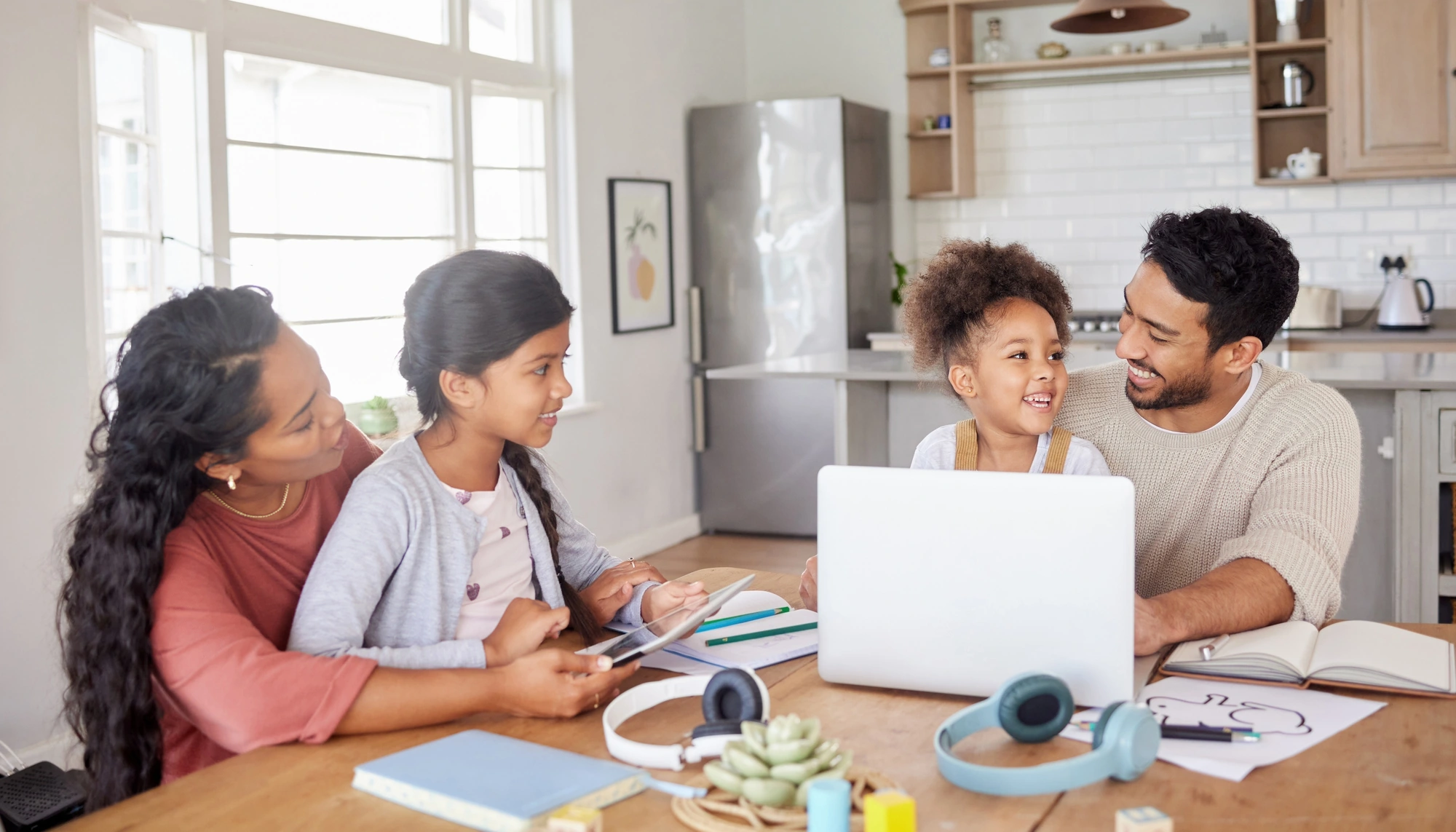 Family of four on a laptop in their kitchen, going over a travel insurance checklist 