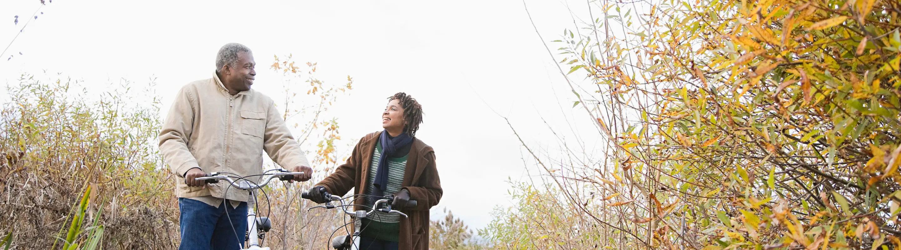 a father and daughter with travel insurance for New York walking their bikes on a nature trail upstate 