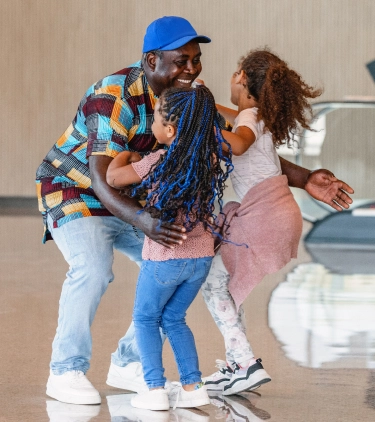 a father with travel insurance for city trips reunites with his two young daughters at the airport after his vacation