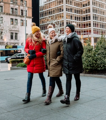 three women with travel insurance for New York, enjoying Christmas tree shopping in New York City