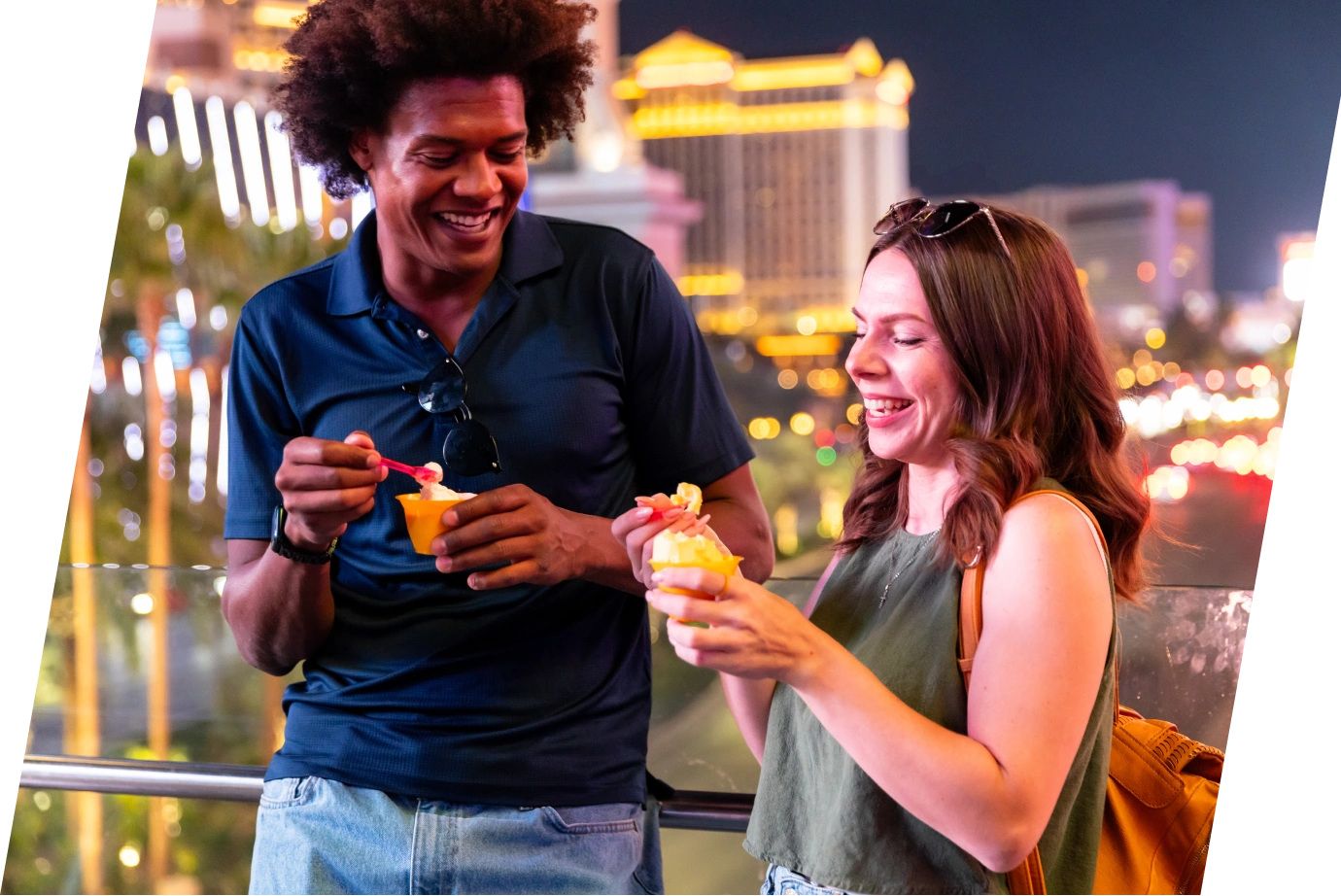 two friends with travel insurance for Nevada, eating ice cream at night with the Las Vagas skyline in the background