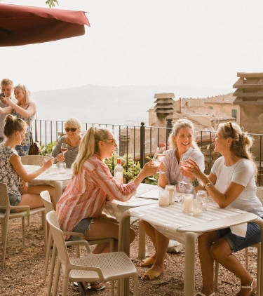 ladies with travel insurance for Europe, enjoy wine at a restaurant in the Mediterranean 