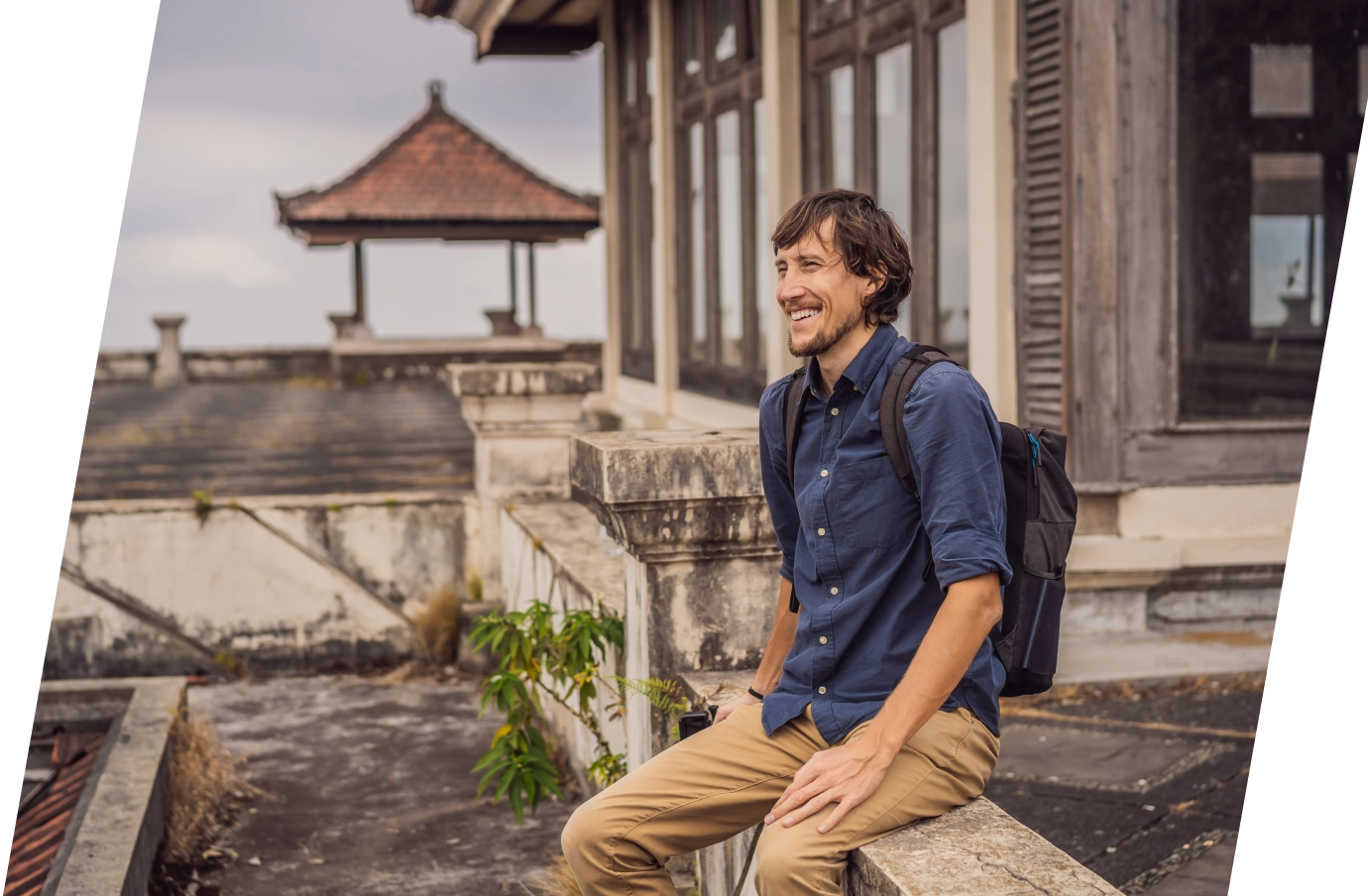 Man with travel insurance for Bali sitting at a temple with a backpack on