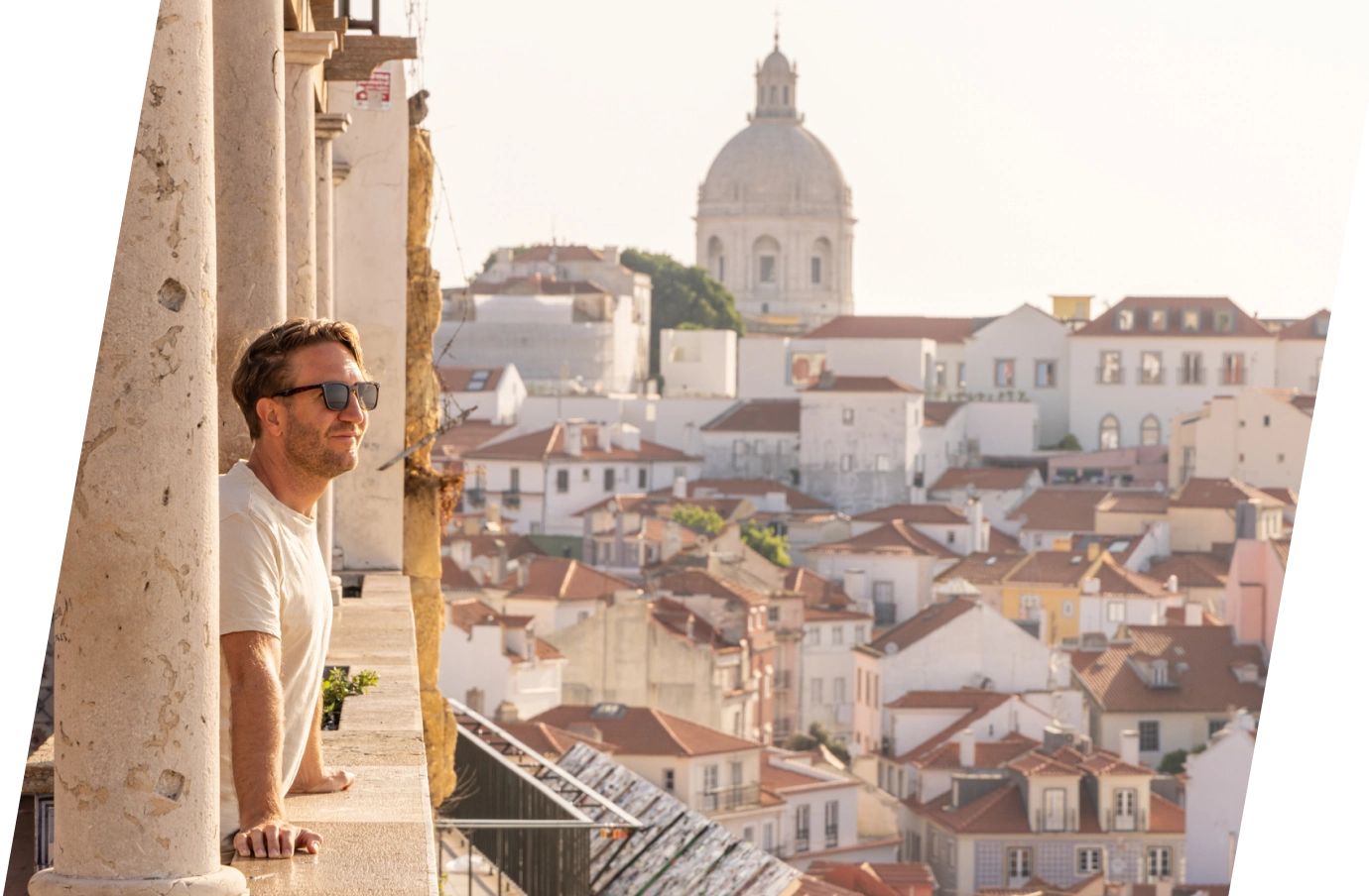 Man with travel insurance for Portugal on a balcony overlooking the Alfama District in the city of Lisbon 