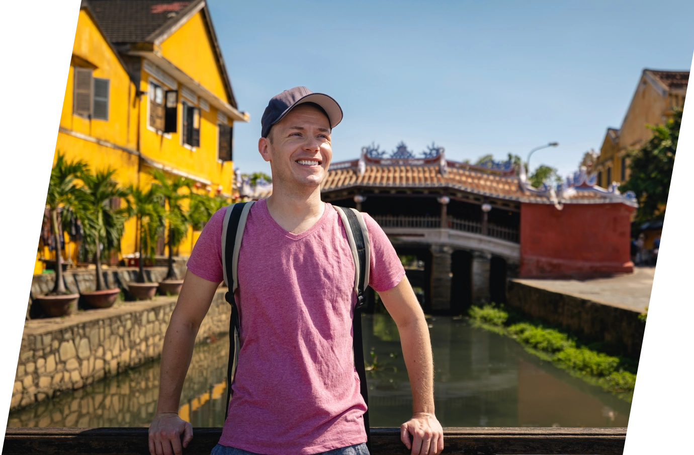 Man with travel insurance for Vietnam standing on a bridge in ancient Hoi An city