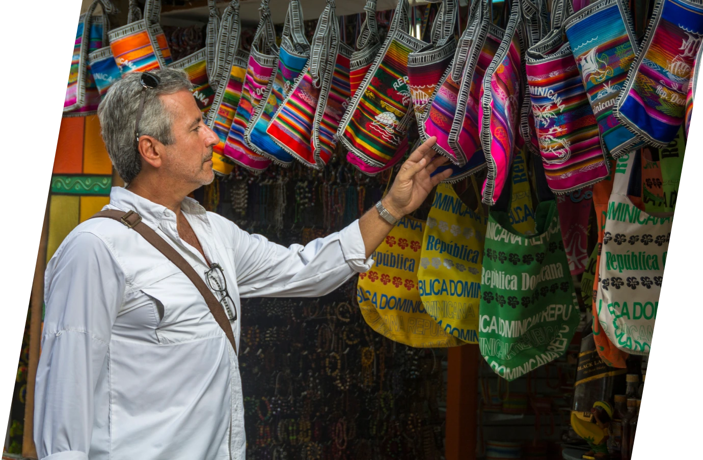 Middle-aged man with travel insurance for the Dominican Republic looking at handmade bags at a market