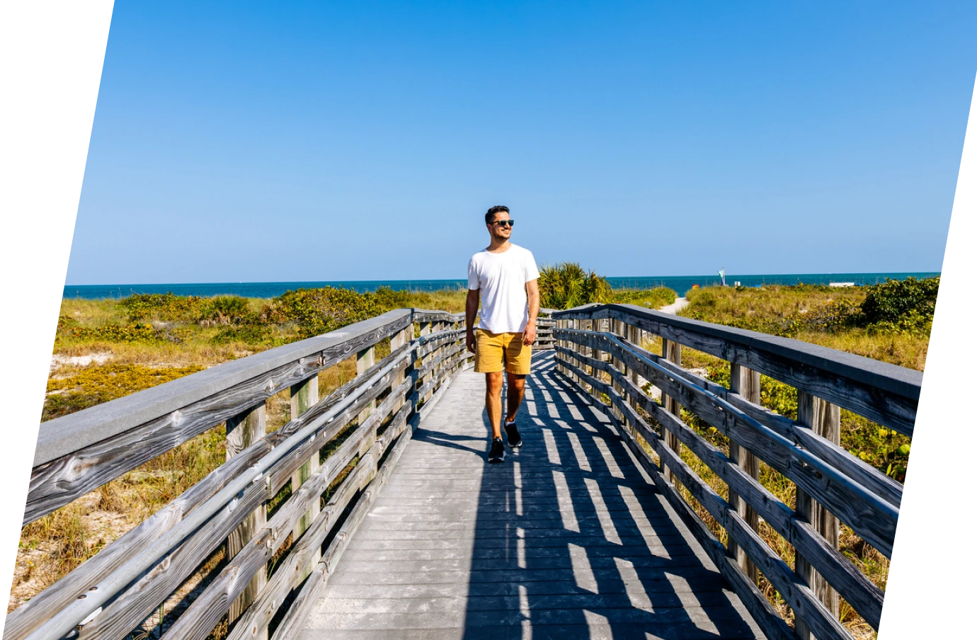 Man with travel insurance for Florida walking down a boardwalk leaving the beach