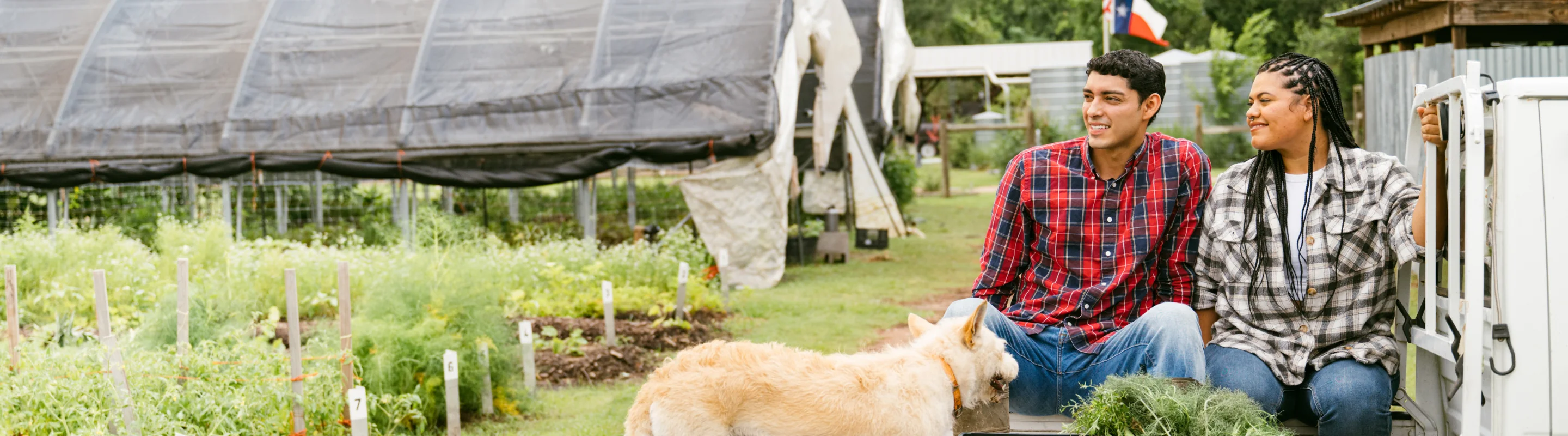 a man and woman, with travel insurance for Texas, relax in a rural farm setting with their dog