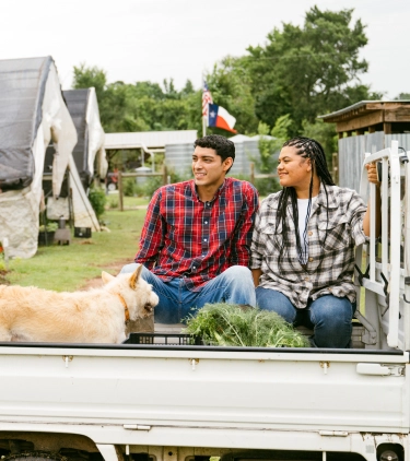 a man and woman, with travel insurance for Texas, relax in a rural farm setting with their dog