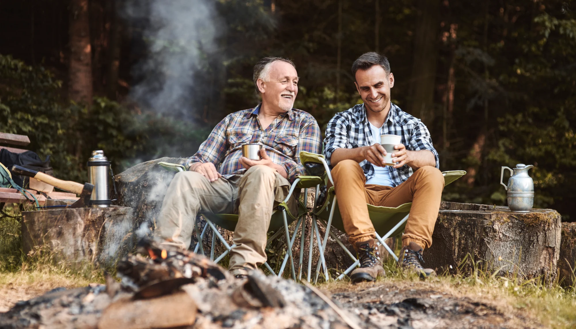 a father and son enjoying a fire while camping, practicing the wildfire safety tips they researched ahead of time