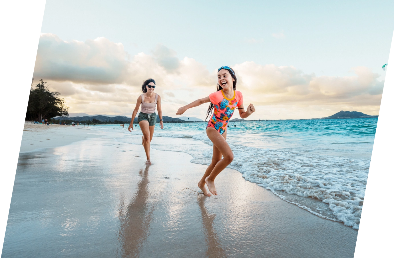 Mother with travel insurance for Hawaii, walking on the beach while her daughter runs in front of her
