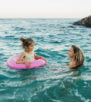 a mother and daughter, swimming in the Mediterranean Sea with travel insurance for Spain