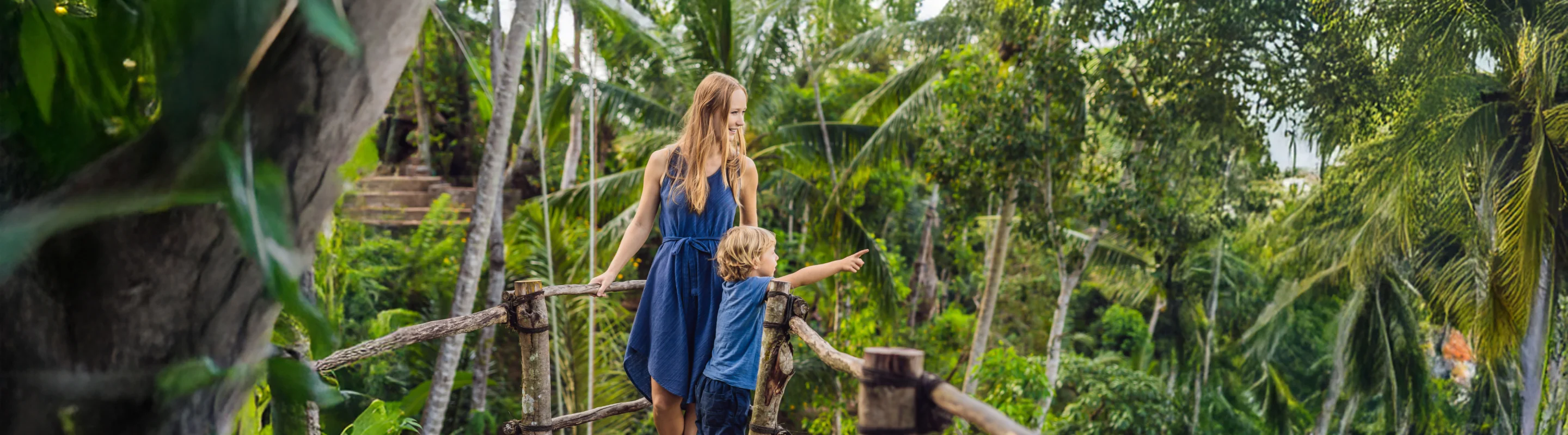 a mother-son duo with travel insurance for the Philippines, birdwatching in a tropical rainforest  