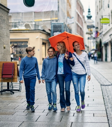 a mother with her teenage kids, walking through a rainy Austrian town and protected by travel insurance for Austria 