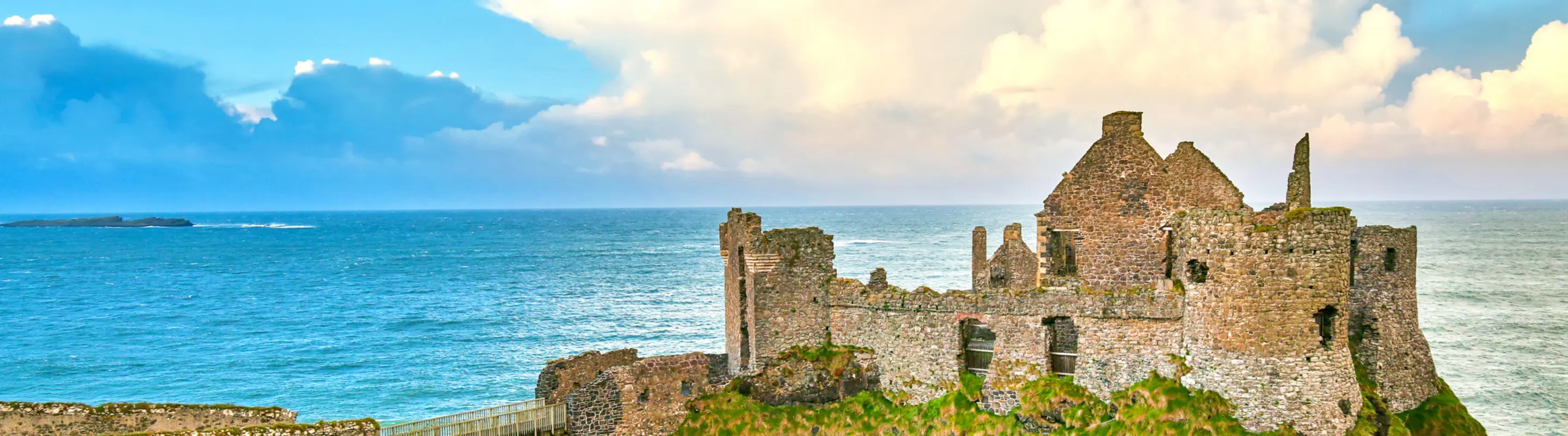 View of Dunluce Castle on a cliff overlooking the ocean, highlighting travel insurance for Ireland